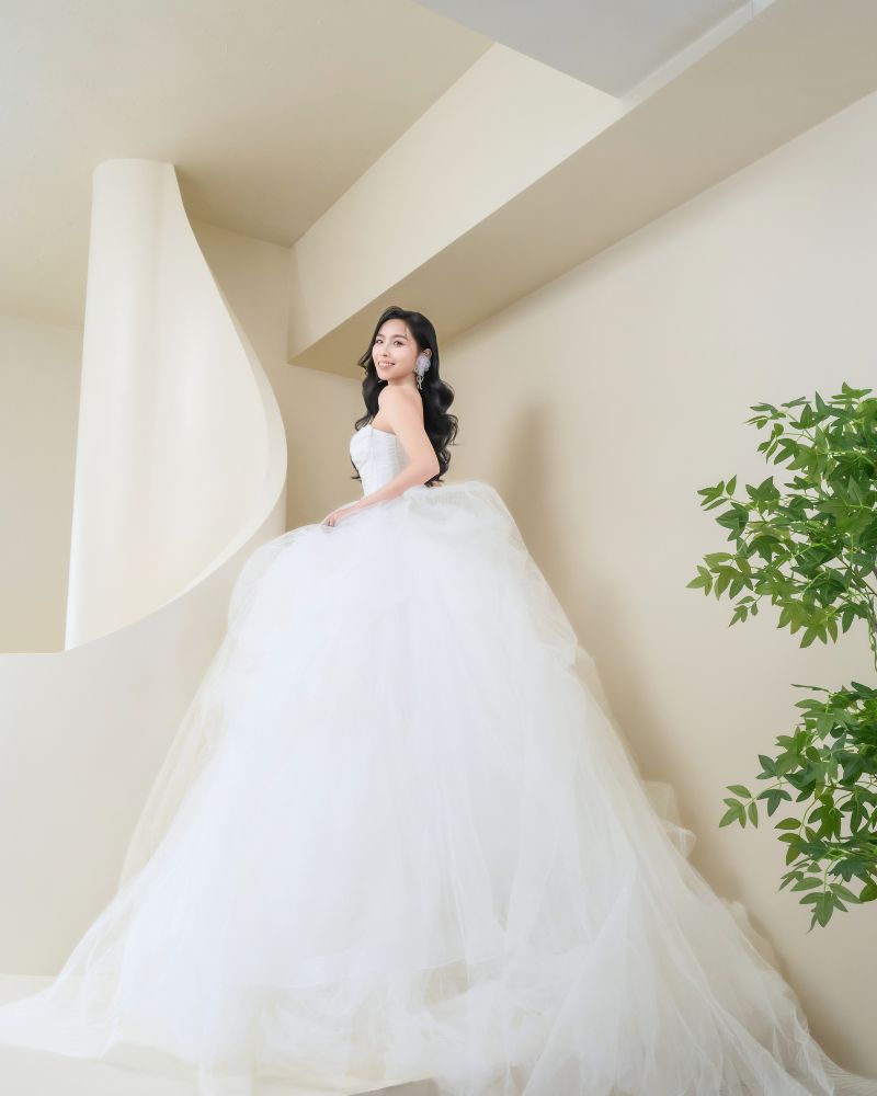 新娘穿著純白色平口蓬裙婚紗站在簡約弧形空間中